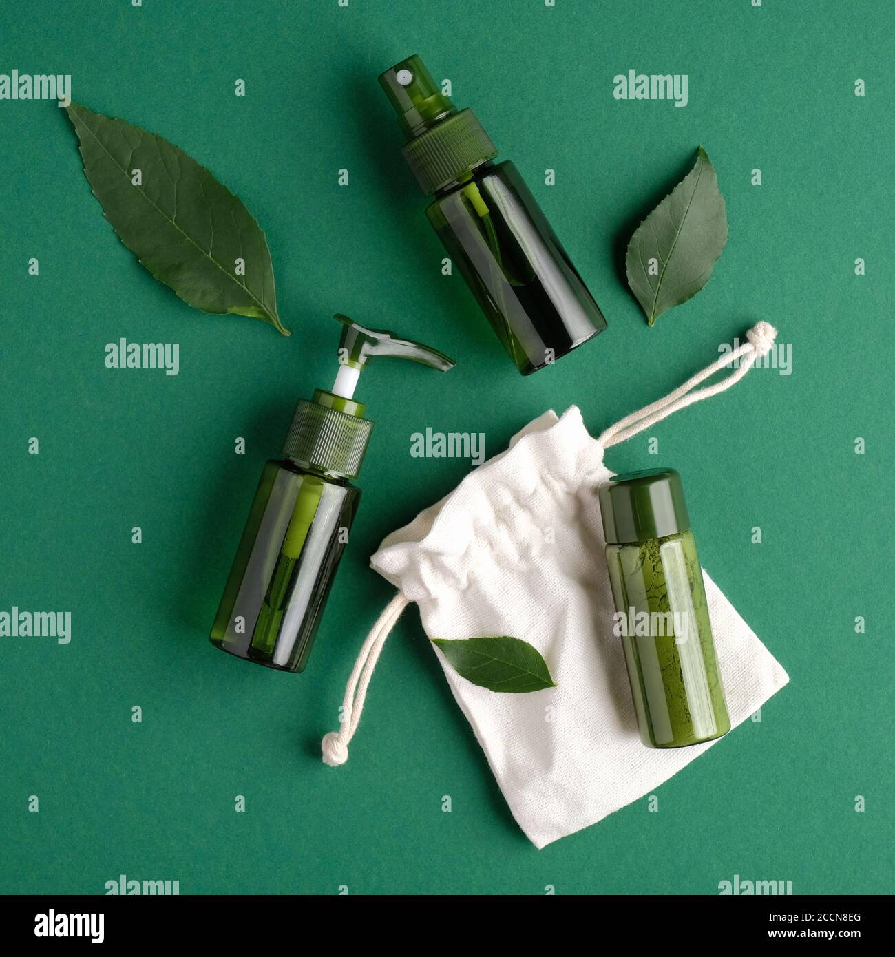 Set di cosmetici zero waste. Posa piatta, vista dall'alto bottiglie di cosmetici verdi, foglie di piante e cassa su sfondo verde. PRODOTTI DI bellezza naturali biologici SPA. Foto Stock