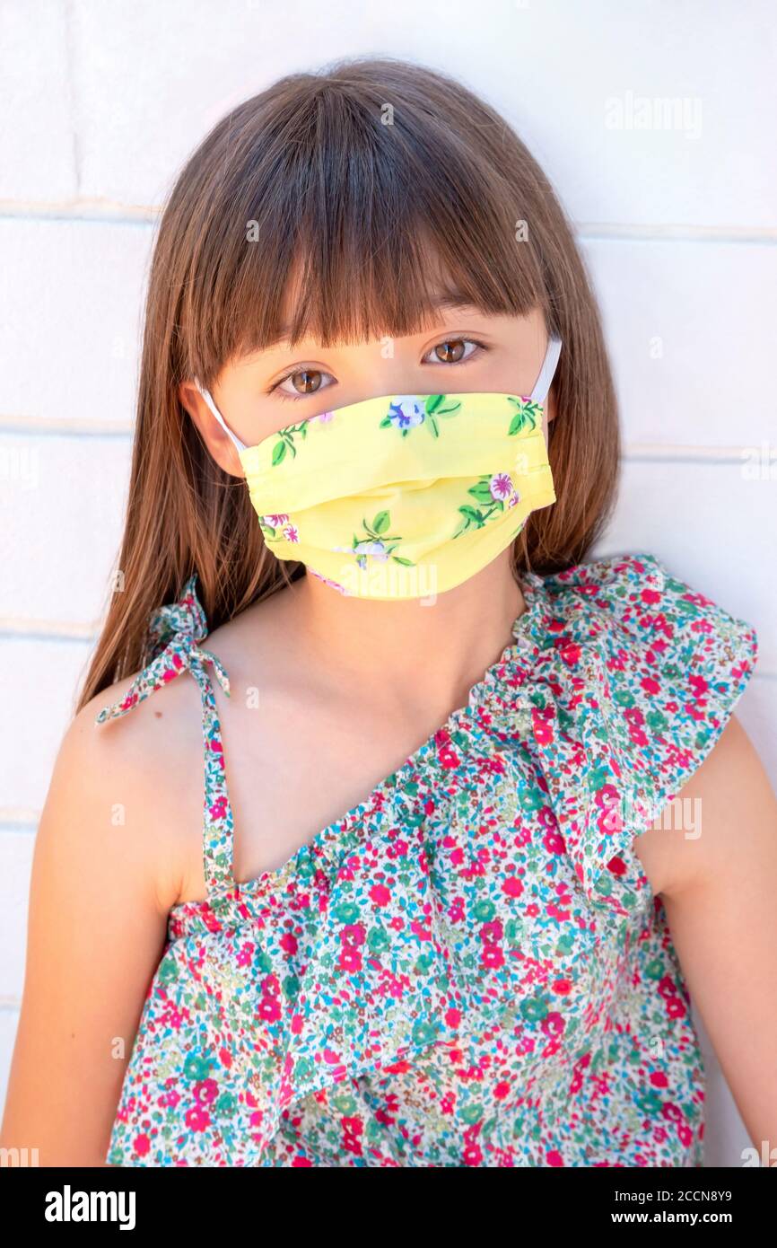 Ragazza di otto anni che indossa una maschera floreale Foto Stock