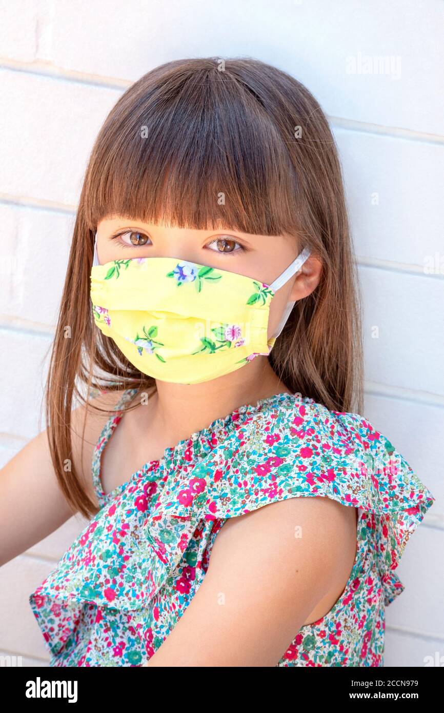 Ragazza di otto anni che indossa una maschera floreale gialla Foto Stock
