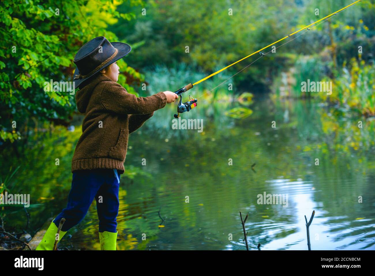 Bambino piccolo che cattura un pesce. Bambino con canna da pesca al lago.  Solitario felice ragazzo che pesca dal lago di spiaggia Foto stock - Alamy