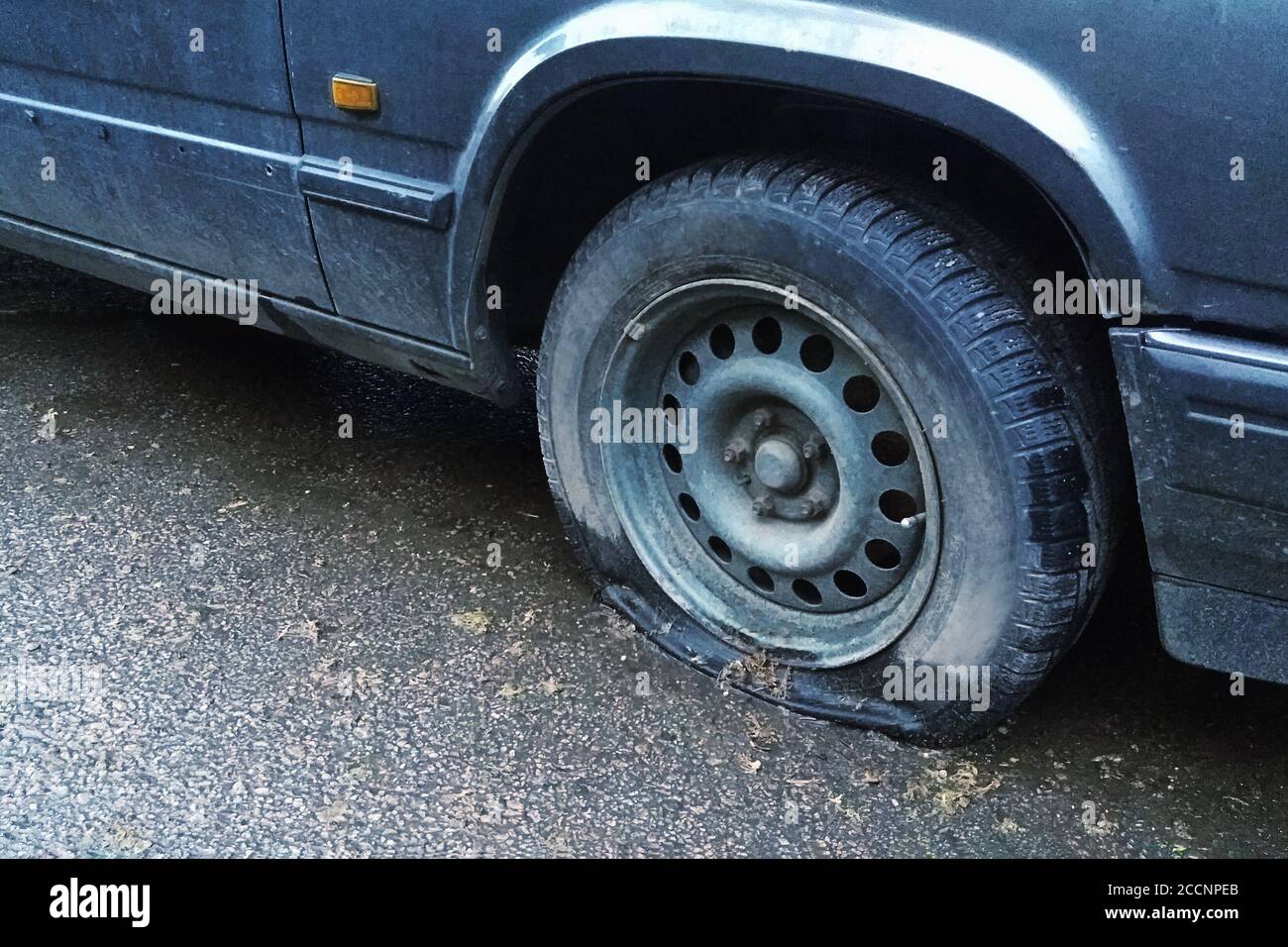 vecchia macchina con pneumatico sgonfio sulla strada, primo piano Foto Stock