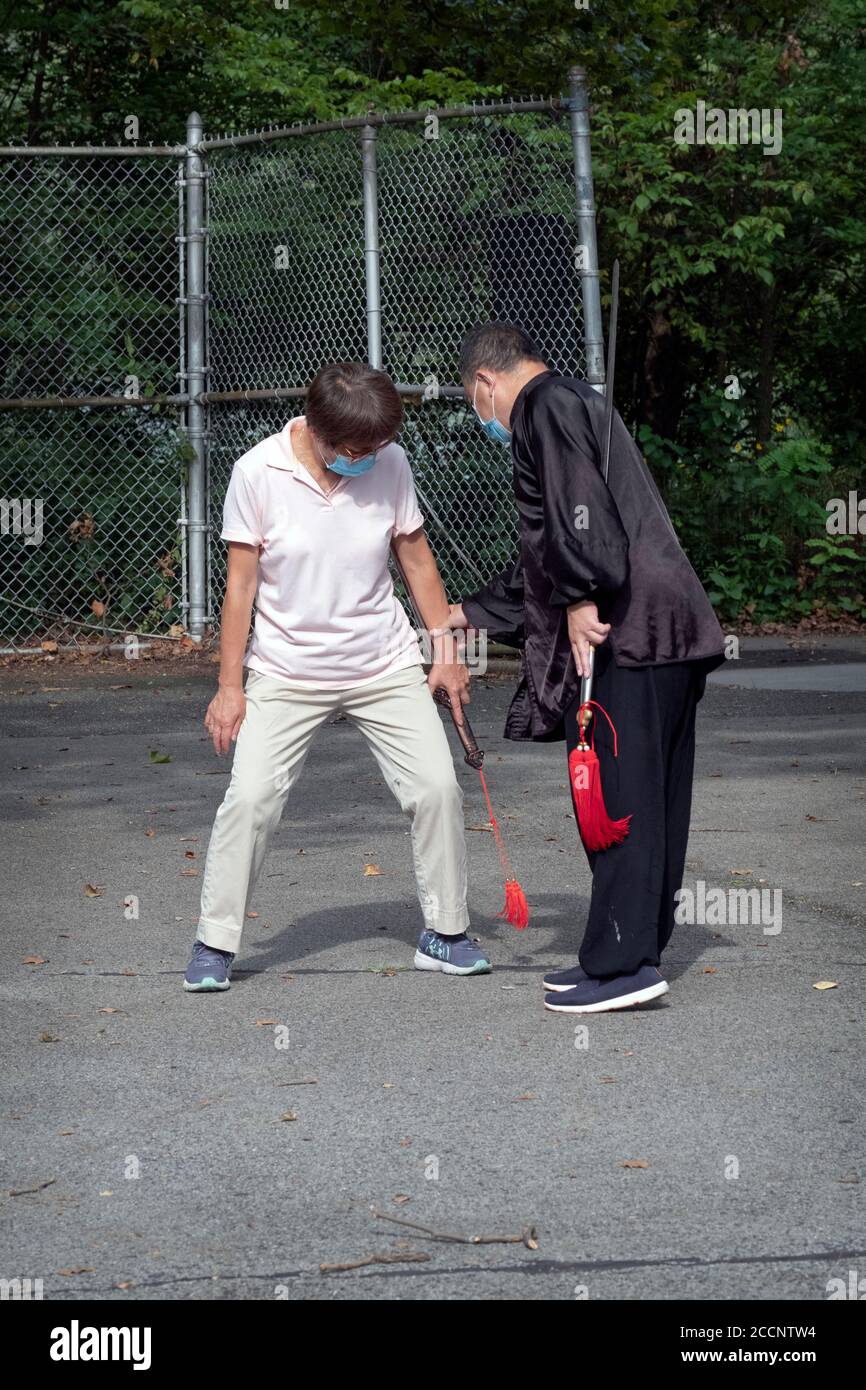 Un insegnante di Tai Chi americano asiatico mostra ad una donna allievo la posizione corretta della mano per un particolare movimento. A Flushing, Queens, New York City. Foto Stock