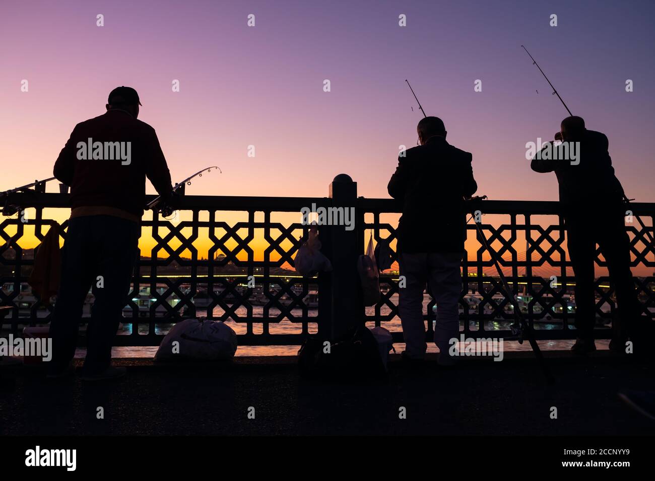Pescatori turchi non identificati sul ponte di Galata al crepuscolo a Istanbul Foto Stock