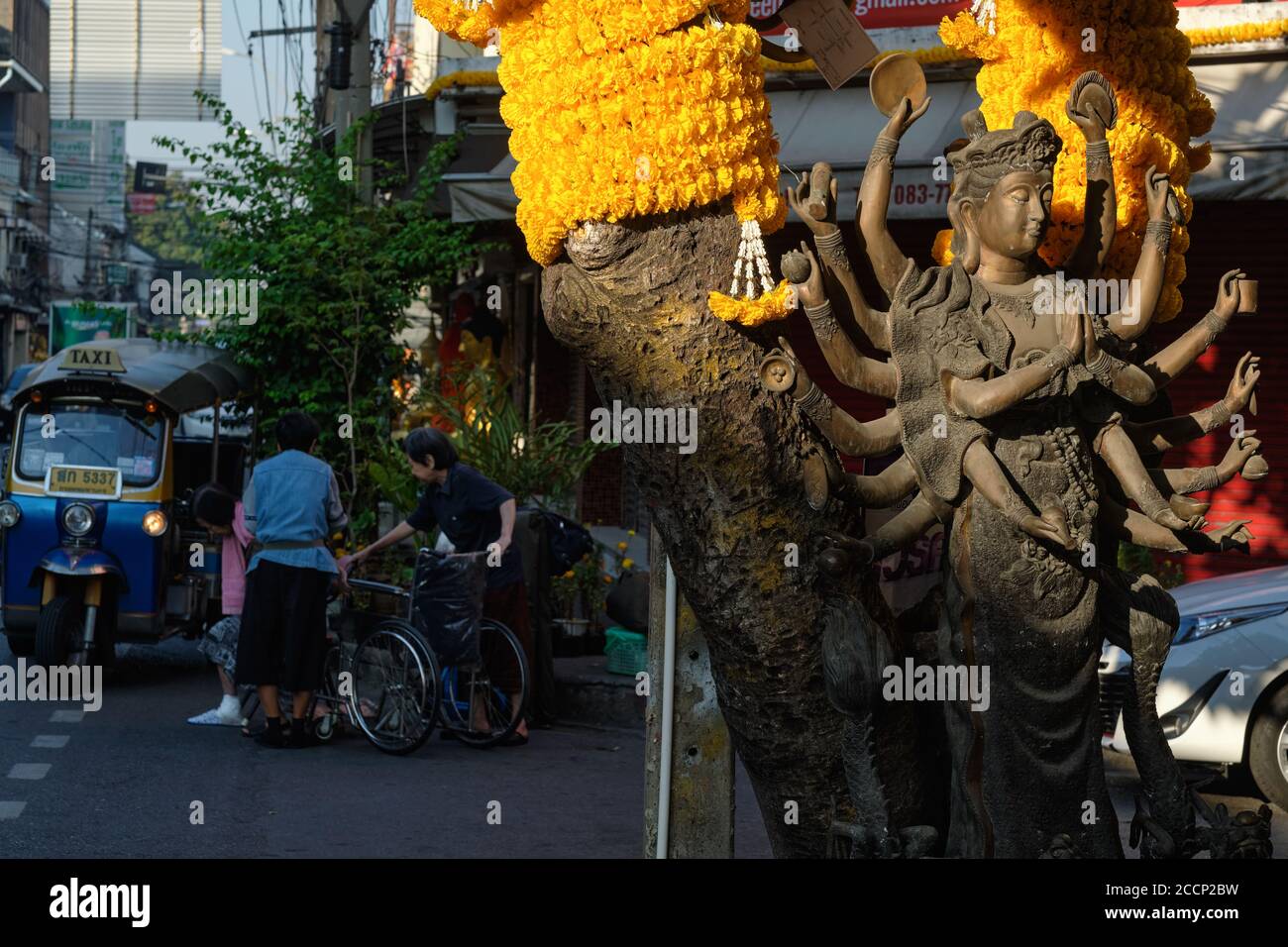 La statua di una dea Taoista multi-armata, indù, illuminata dalla luce del mattino presto, in piedi a Bambung Muang Rd., Bangkok, Thailandia Foto Stock