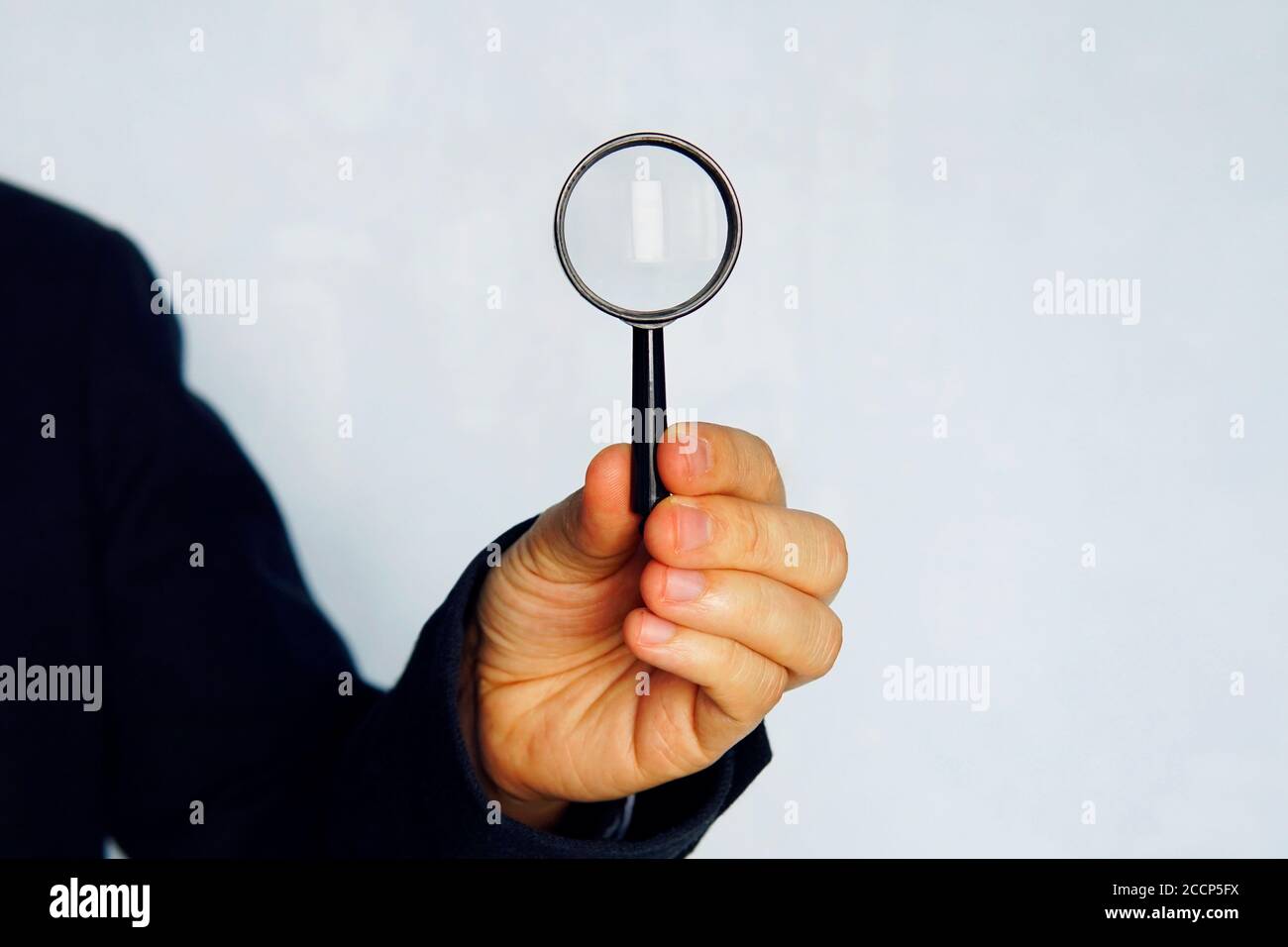 concetto di ricerca. Primo piano di uomo d'affari in tuta blu con lente di ingrandimento su sfondo blu Foto Stock
