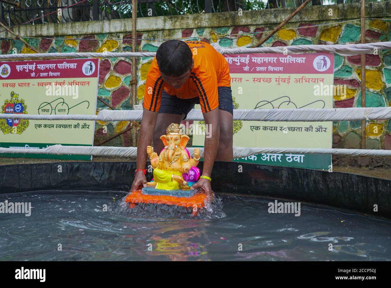 Immersione dell'idolo di Ganesh nelle restrizioni pandemiche del COVID 19. Ganpati Visarjan in uomo fatto stagno persone con maschera -Mumbai, Maharashtra / India. Foto Stock