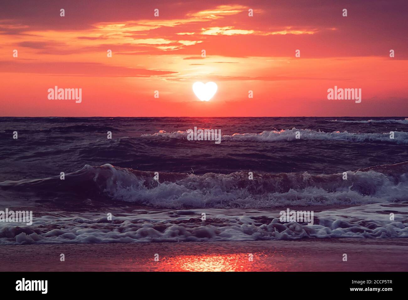 Il cuore cammina verso il tramonto sul mare in nuvole scure. Amore passato. Separazione. Concetto. Il sole è il cuore è la sera prima del tramonto. San Valentino Foto Stock