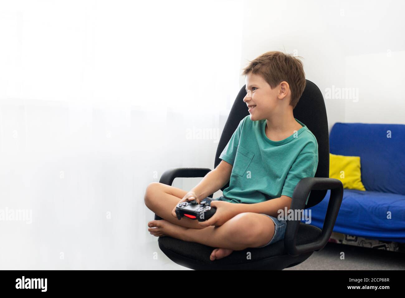 Boy gioca un gioco per computer con le cuffie e un joystick, console di gioco. Foto Stock