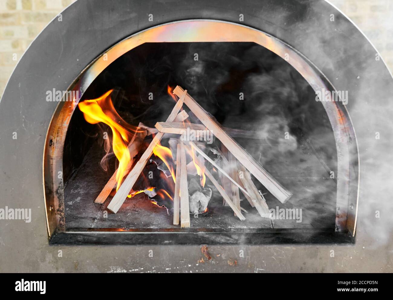 Carta e legno acceso che emette fiamme e fumo dopo essere stato acceso in un forno per pizza. Foto Stock