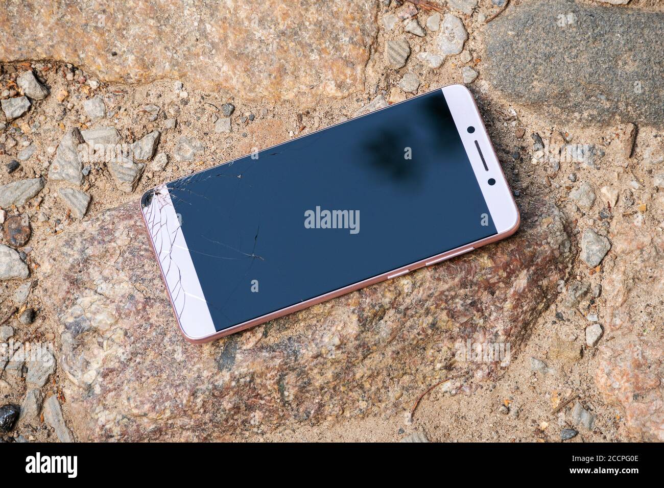 il nuovo telefono rosa con lo schermo rotto giace sulle rocce Foto stock -  Alamy