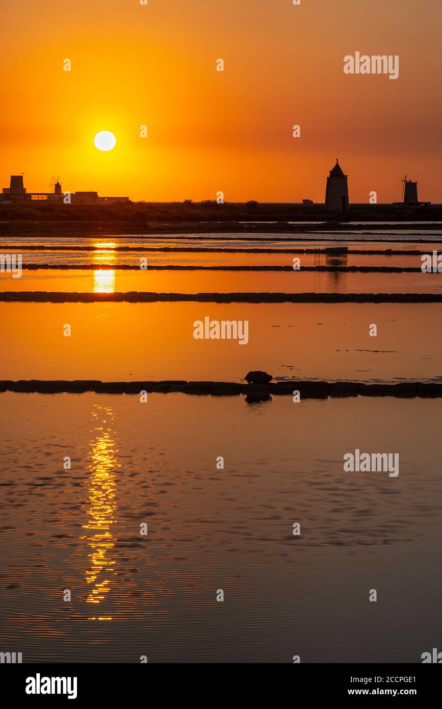 Tramonto tra le saline e mulini a vento presso la riserva naturale vicino a Nubia, a sud di Trapani, sulla costa occidentale della Sicilia, Italia. Foto Stock