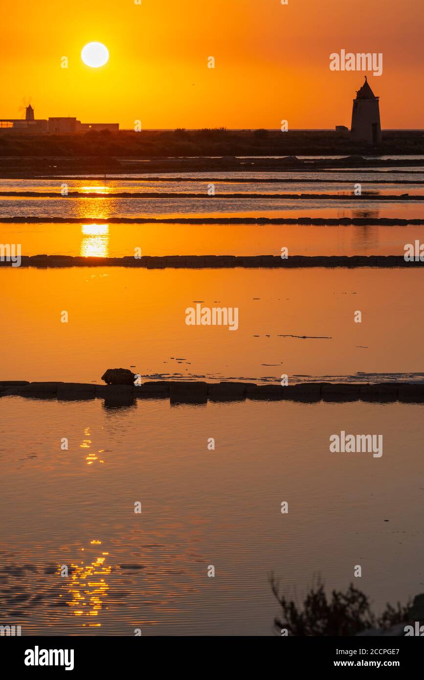 Tramonto tra le saline e mulini a vento presso la riserva naturale vicino a Nubia, a sud di Trapani, sulla costa occidentale della Sicilia, Italia. Foto Stock