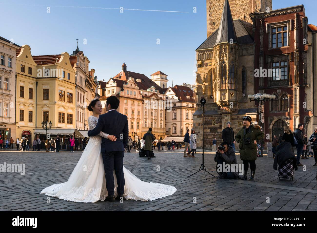 La coppia di nozze posa nella luce del mattino presto, Piazza della Città Vecchia, (Staromestske namesti), guardando verso la torre del Municipio Vecchio, Praga Foto Stock