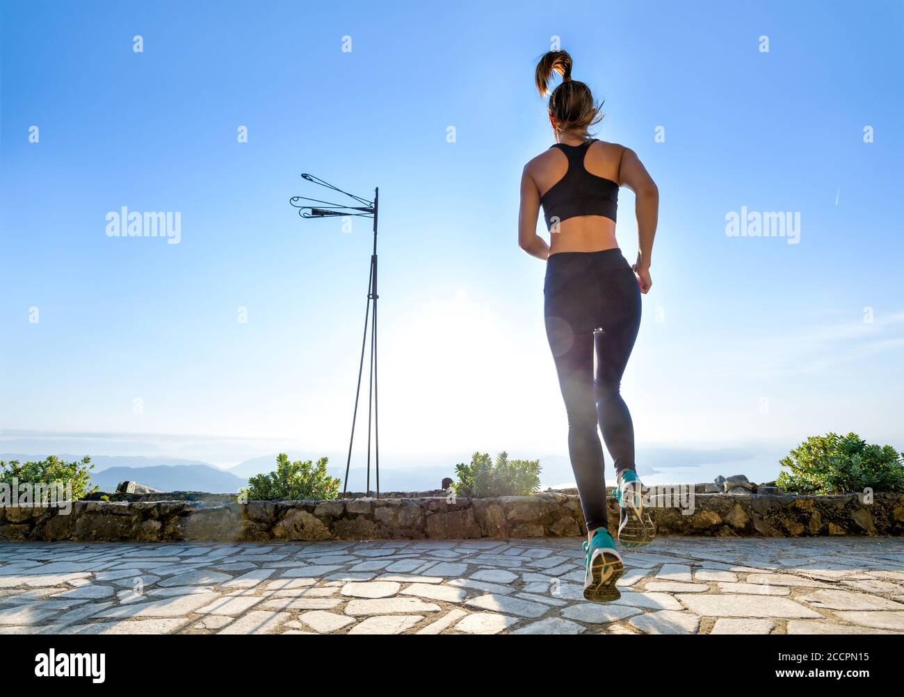 Addestramento della donna che fa un workout cardiovascolare che fa salti sul all'aperto, nel giardino, potrete praticare una forma di salute e fitness concetto al sole della mattina presto Foto Stock