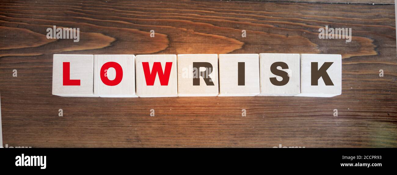 Parole a basso rischio scritte su cubetti di legno. Valutazione del rischio finanziario, ricompensa del rischio e concetto di gestione del rischio di portafoglio. Foto Stock
