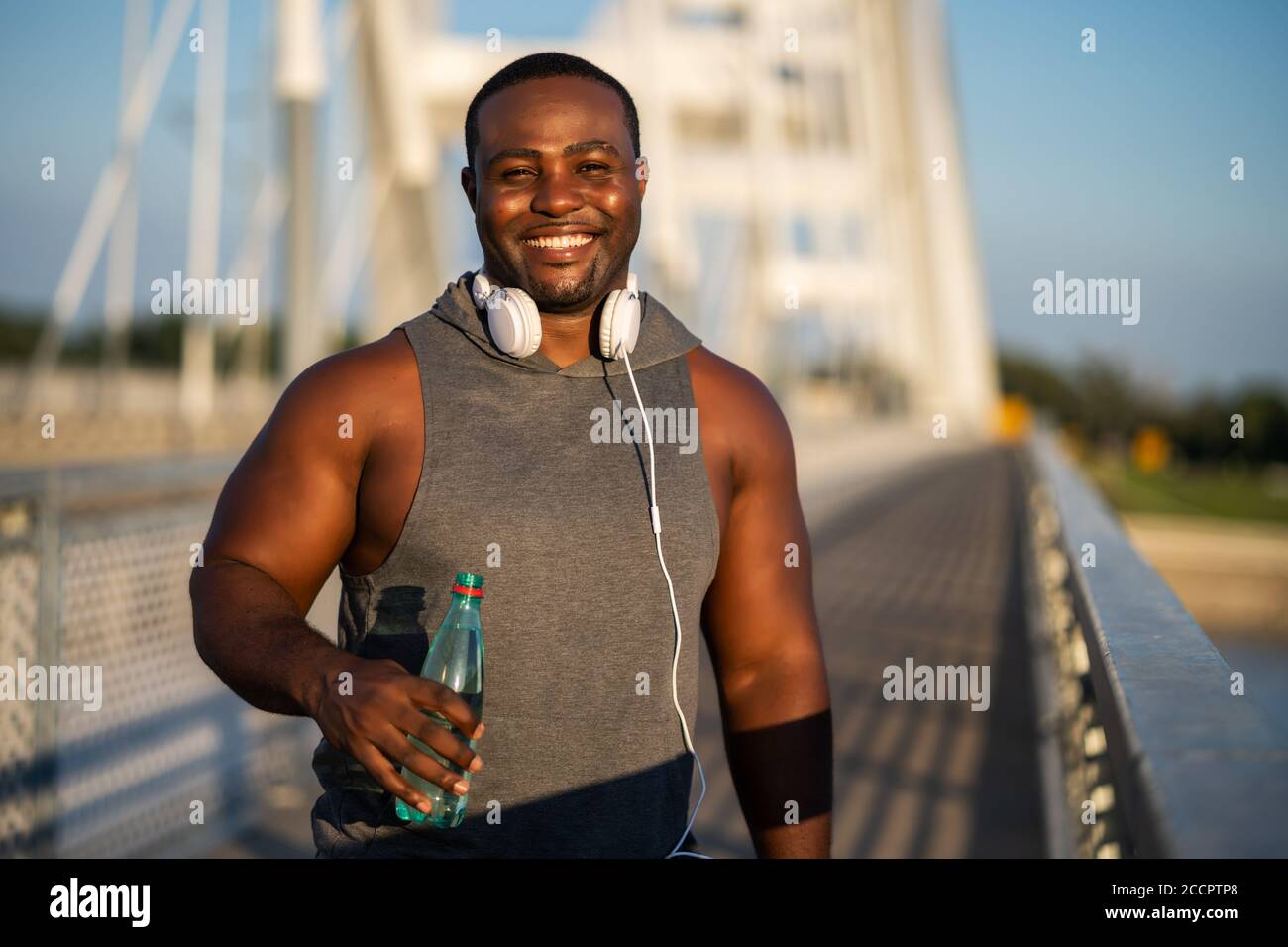Ritratto di giovane allegro afroamericano in abbigliamento sportivo che guarda la macchina fotografica e sorridente. Foto Stock