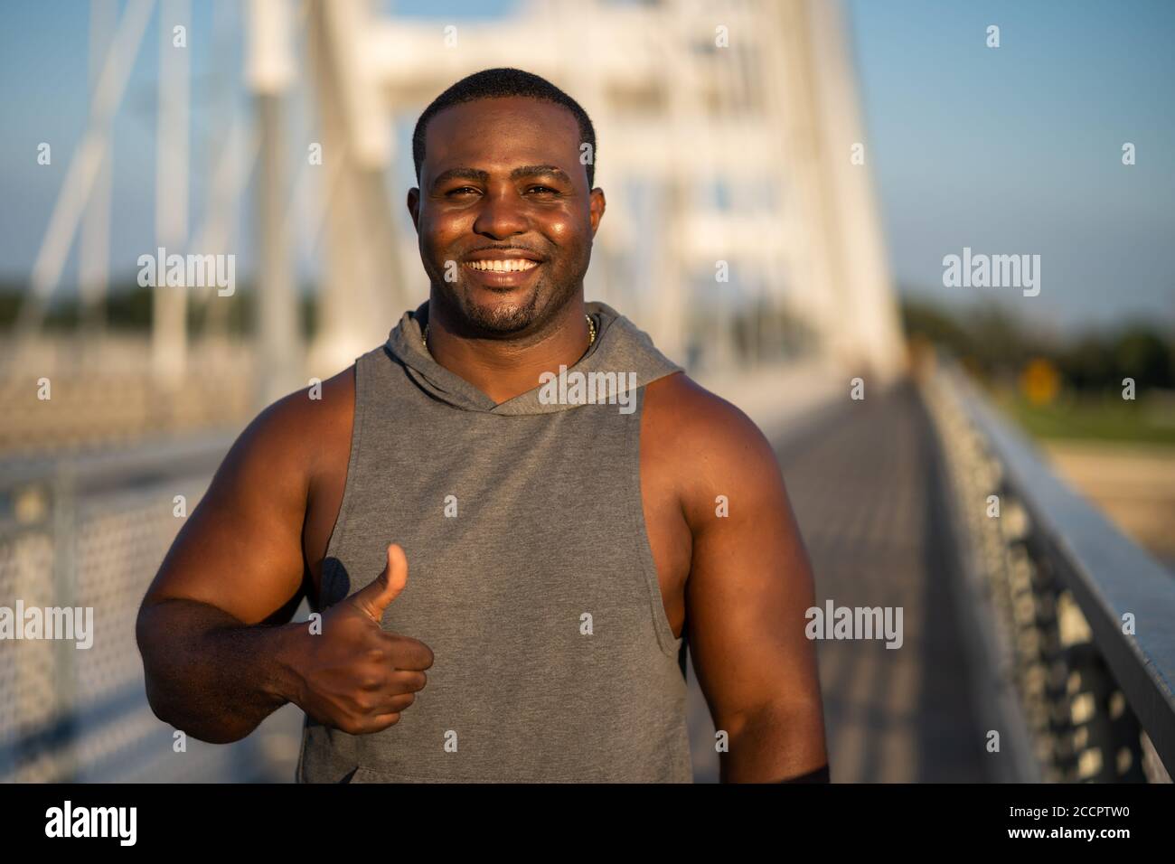 Ritratto di giovane allegro afroamericano in abbigliamento sportivo che guarda la macchina fotografica e sorridente. Foto Stock