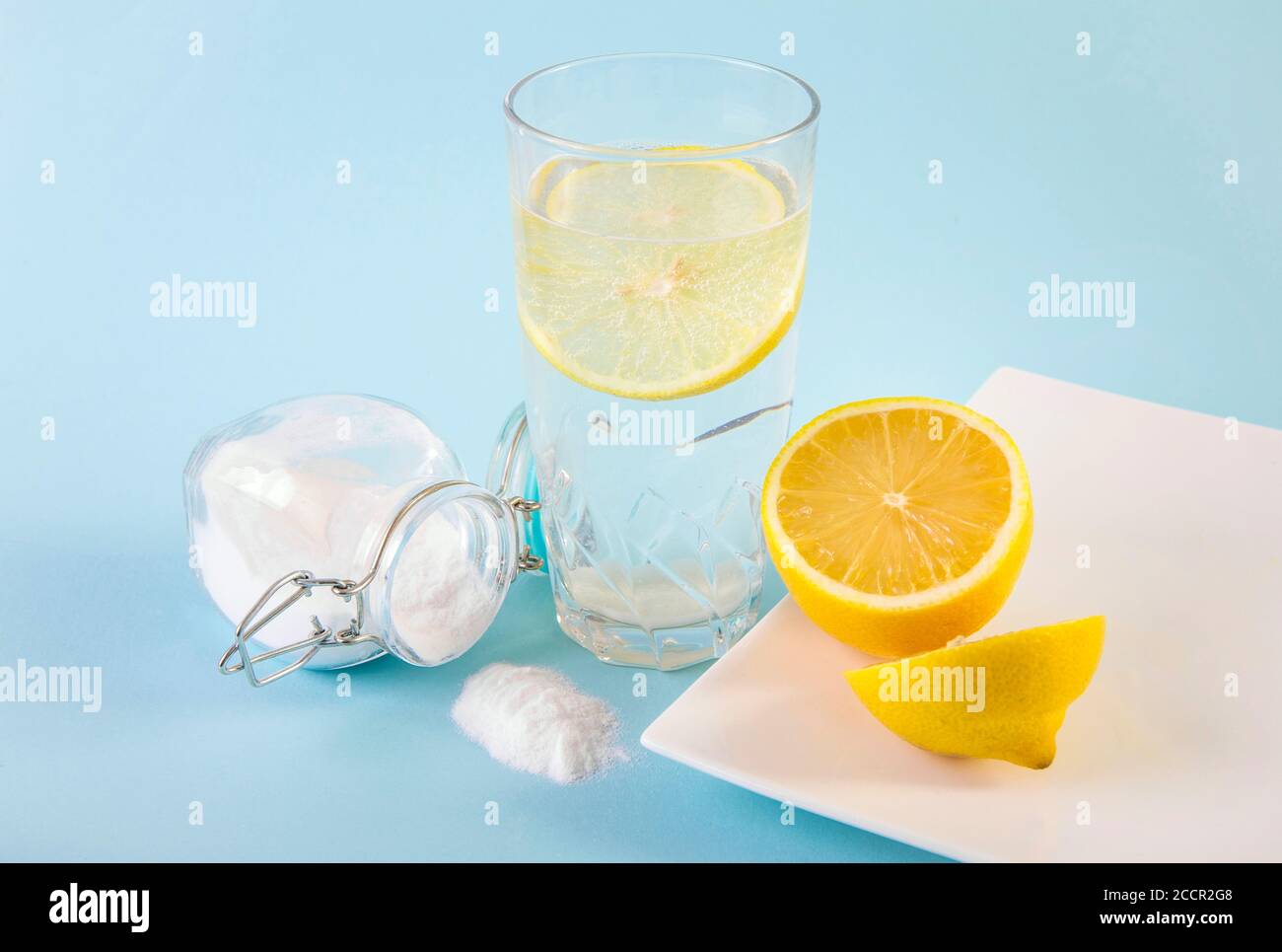 Bicarbonato di sodio in bicchiere da bere con acqua e succo di limone, benefici per la salute per il sistema digestivo concetto. Sfondo blu chiaro. Foto Stock