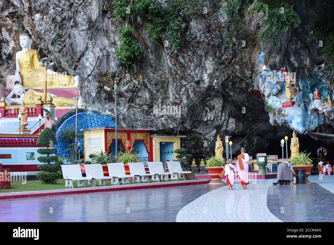 Donne monaci che entrano in una pagoda costruita all'interno di una grotta. Monaci femminili che passano dalla statua del Buddha reclinata all'interno del tempio. HPa An, Myanmar, Birmania, Asia Foto Stock