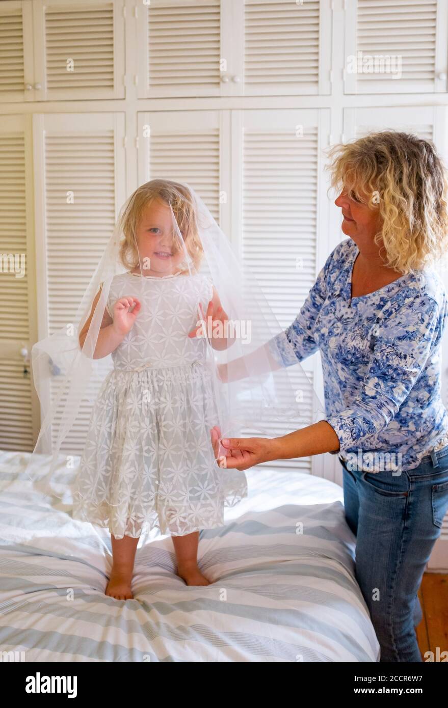 Bambino giovane femmina 3 anni vestirsi in un vecchio abito da sposa originariamente indossato da sua nonna 56 anni prima Foto Stock