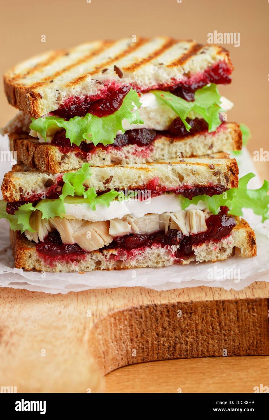 Delizioso sandwich di tacchino o pollo con brie o Camembert formaggio, lattuga e mirtillo (lingonberry, bacca di gallina) chutney sul pane di grano con lino vedere Foto Stock