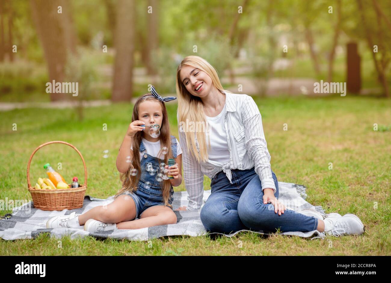 Ragazza e sua madre che soffia bolle divertendosi a Park Foto Stock