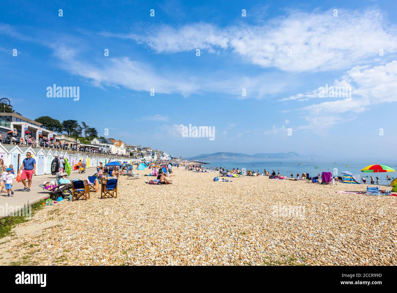 La spiaggia sassosa e lungomare in alta stagione a Lyme Regis, una popolare località balneare sulla Costa Jurassic a Dorset, Inghilterra sud-occidentale Foto Stock