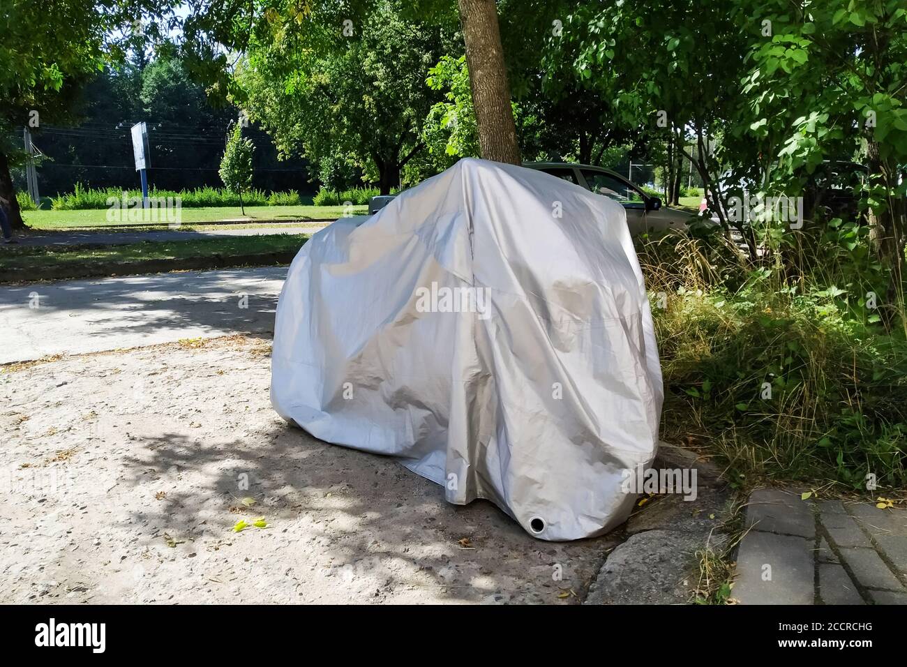 Motocicletta coperta con copertura nel cortile Foto Stock
