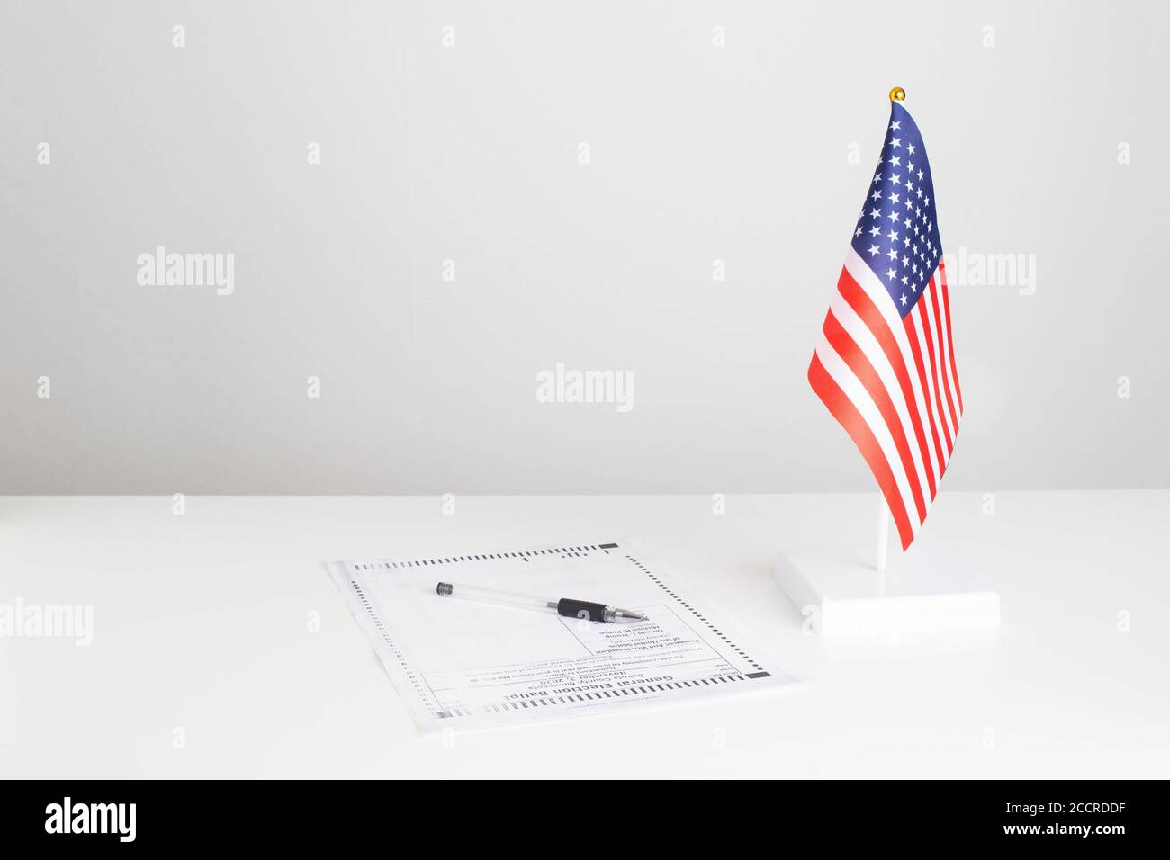 La penna e il documento elettorale per le elezioni presidenziali sono sul tavolo, la bandiera americana su sfondo bianco. Concetto DI elezione presidenziale DEGLI STATI UNITI Foto Stock