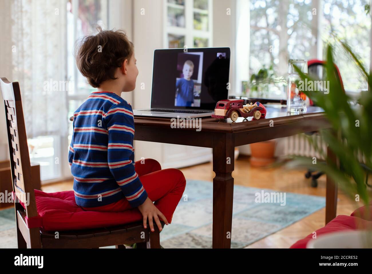 Little Child avere una chat online o una lezione con un Computer portatile a casa Foto Stock