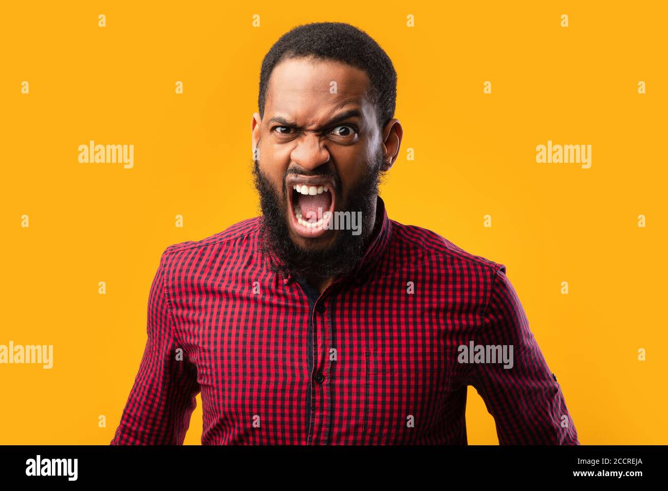Arrabbiato afro uomo urlando allo studio giallo Foto Stock