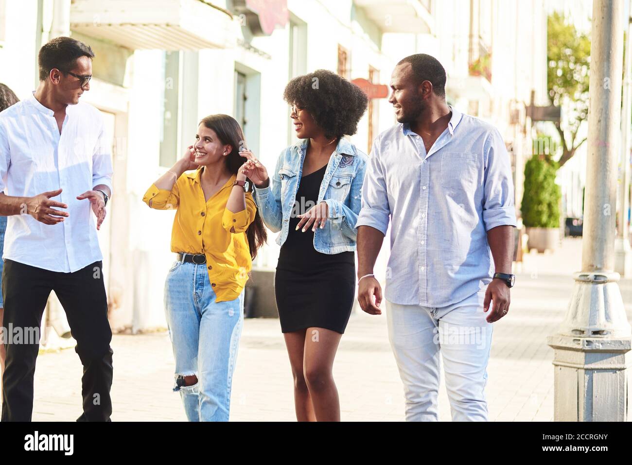 Amici di diverse nazionalità passeggiano per la città e parlano di argomenti diversi. Foto Stock