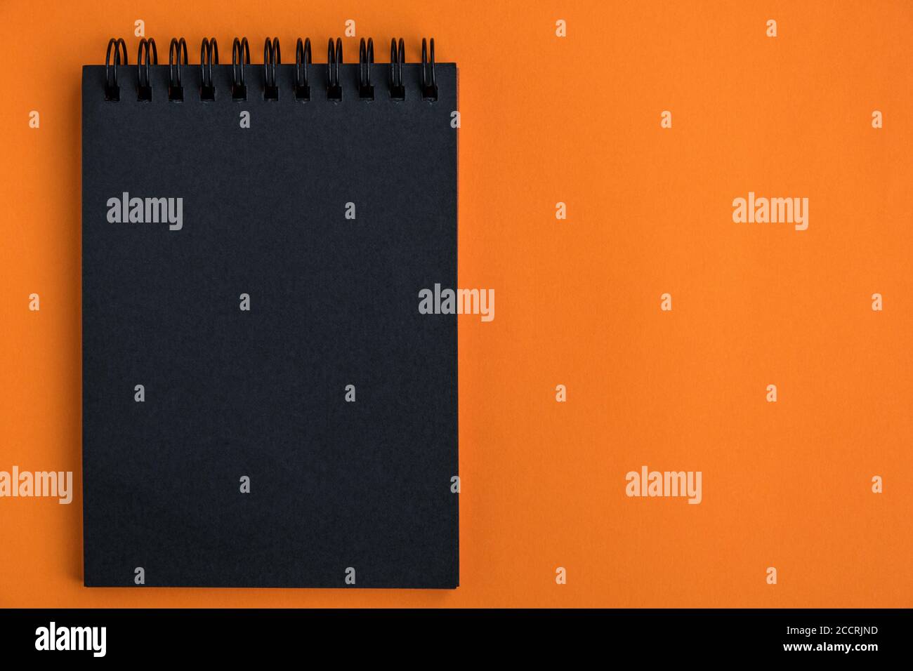 Blocco note nero vuoto su sfondo arancione. Design minimalista halloween celebrazione. Bock up. Vista dall'alto, spazio di copia. Disposizione piatta. Foto Stock
