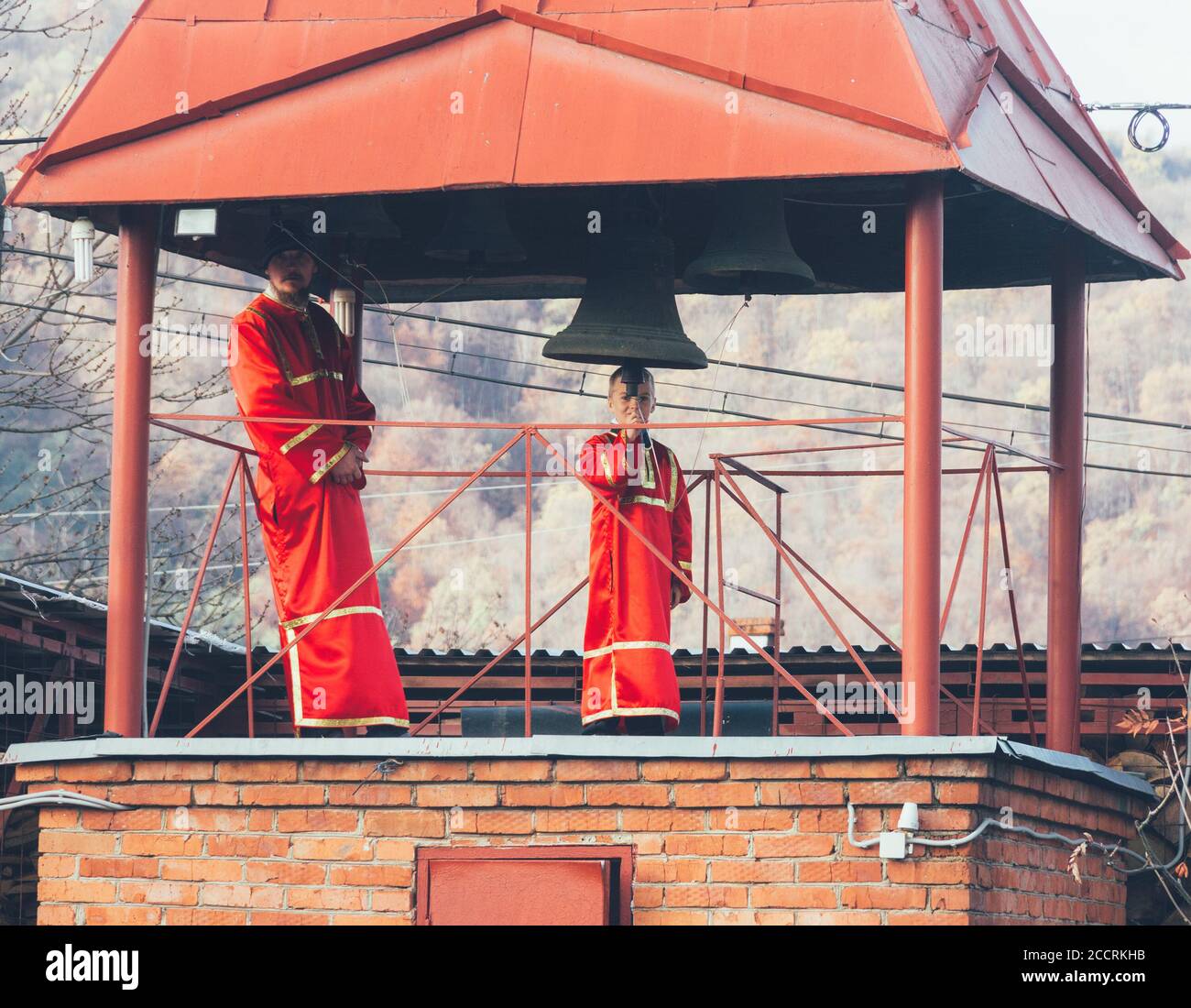 Adygea, Russia - 8 novembre 2017: L'uomo e il ragazzo si inanellano in tombini rossi nel campanile Foto Stock