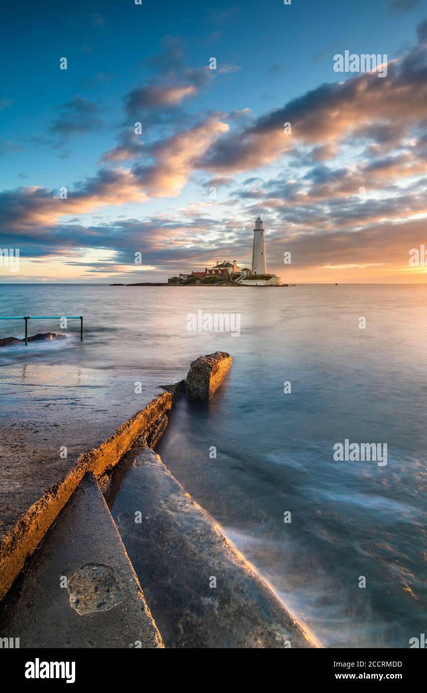 In piedi sui gradini che guardano fuori sopra la strada rialzata con sole e mare ai vostri piedi per l'alba a St Faro di Marys Whitley Bay Northumberland Foto Stock