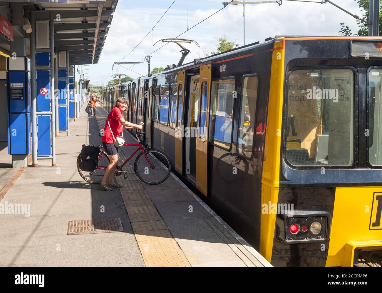Ciclista femminile matura con imbarco in bicicletta Tyne e indossare il treno Metro a South Hylton stazione, nord-est Inghilterra, Regno Unito Foto Stock