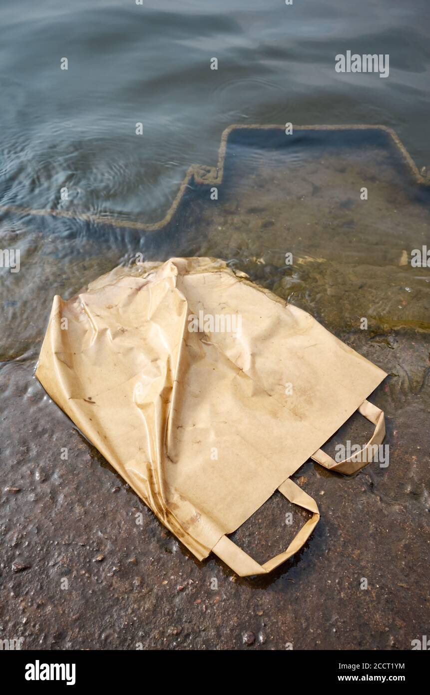 Sacchetto di carta da shopping scartato in acqua, immagine del concetto di inquinamento ambientale. Foto Stock