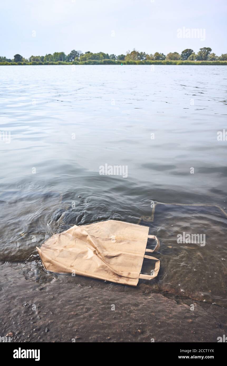 Sacchetto di carta da shopping scartato in acqua, immagine del concetto di inquinamento ambientale. Foto Stock