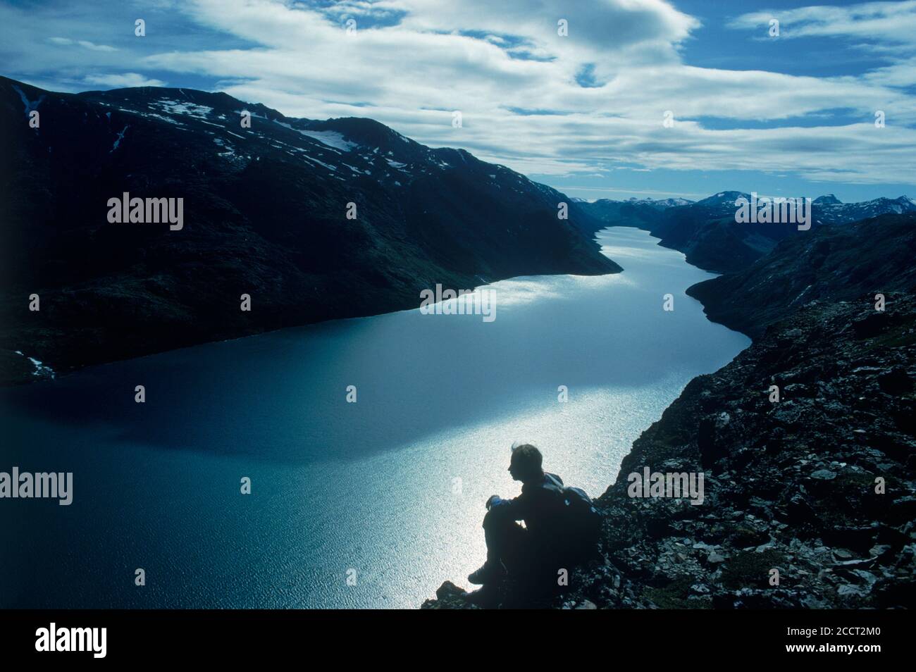 Escursionista seduta al di sopra di Gjende (o) Gjendin Lago in Jotunheimen montagne in Norvegia il parco nazionale di Jotunheimen Foto Stock
