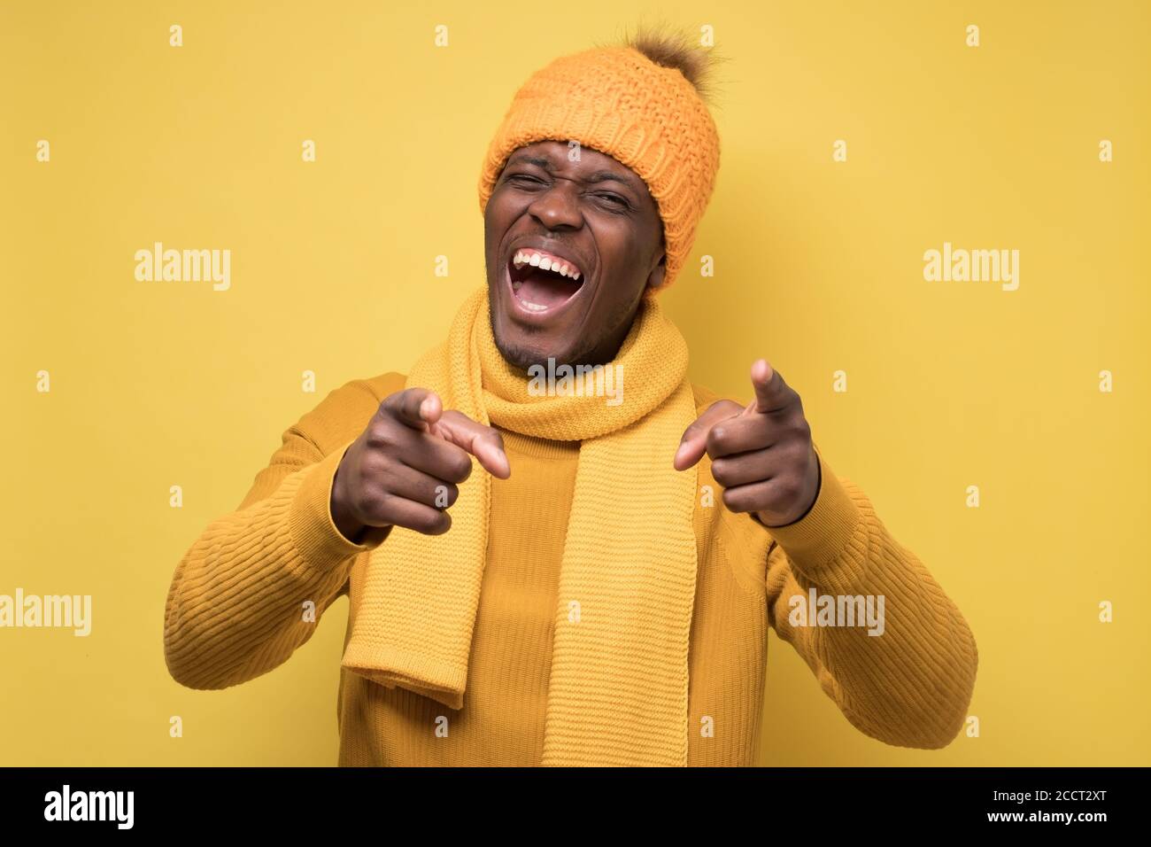 Uomo africano in maglia gialla e cappello caldo che punta a