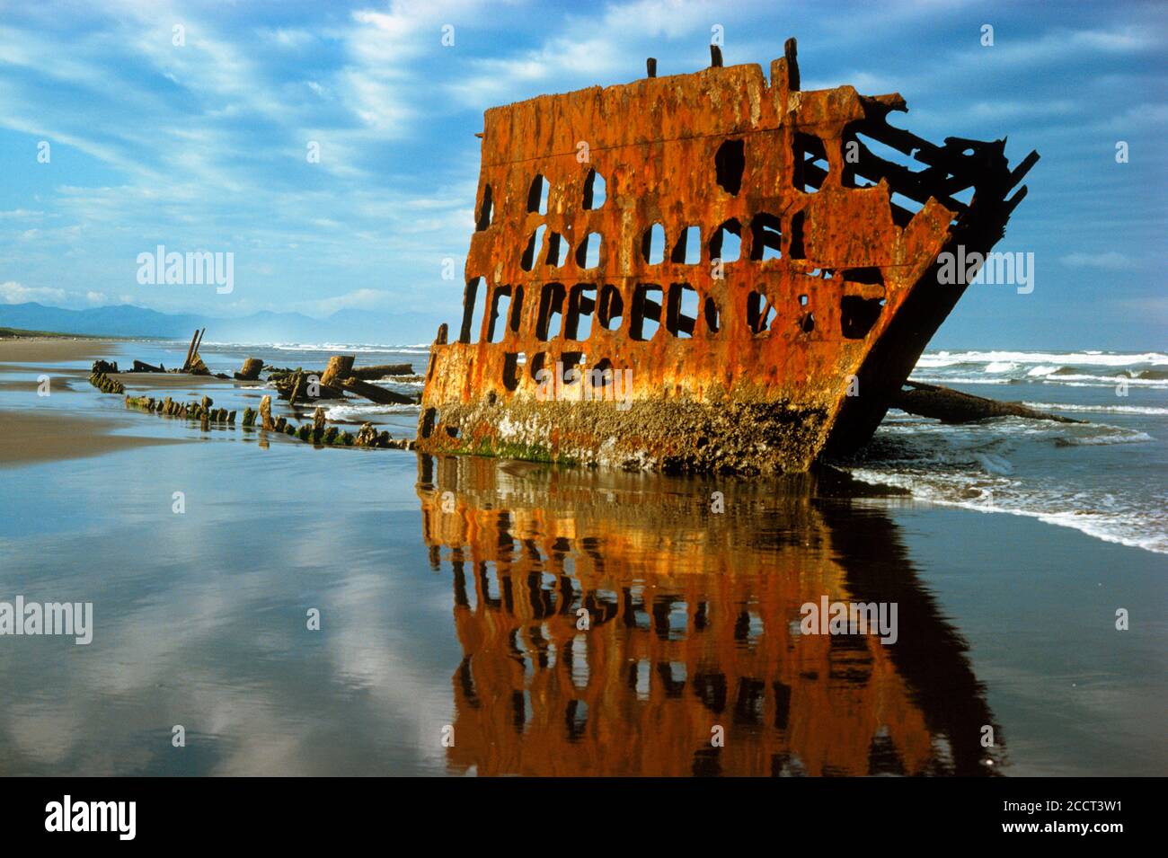 Scafo arrugginito e silhouette della vecchia nave sommersa Peter Iredale ON La costa dell'Oregon settentrionale si riflette sulla spiaggia di sabbia bagnata Foto Stock