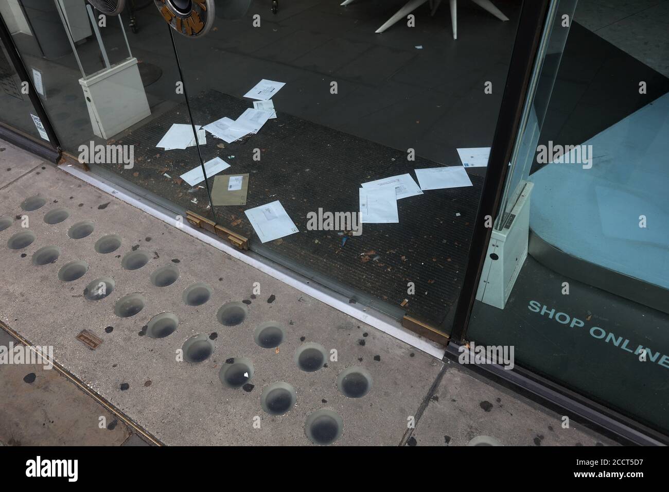 Lettere e bollette si accumulano sul tappetino della porta di un negozio chiuso a Brompton Road, Londra, Regno Unito. Foto Stock