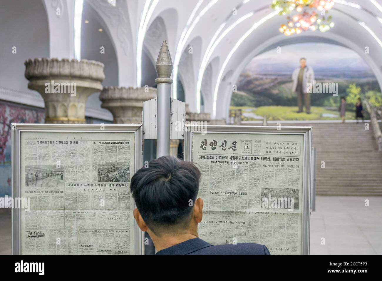 Un commuter legge un giornale su una piattaforma di una stazione della metropolitana di Pyongyang, Corea del Nord Foto Stock