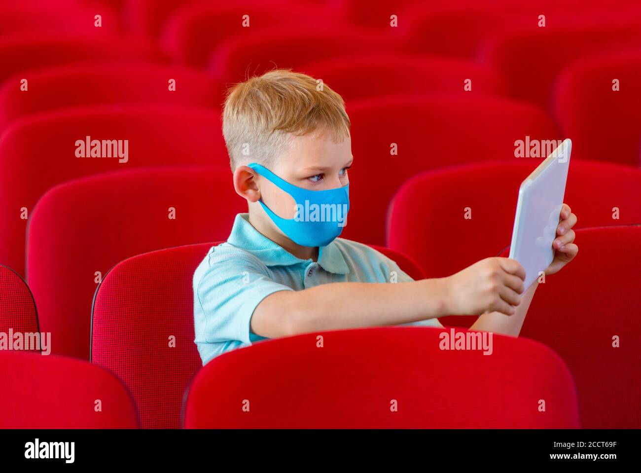 Bambino di scuola con maschera blu contro virus e tablet a lezione. Ritorno sicuro a scuola durante il concetto pandemico. Distanza sociale per combattere COVID-19 Foto Stock
