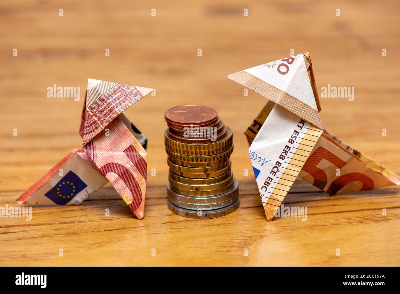 Uccelli Origami in banconote da 10 e 50 euro circa una pila di monete in euro Foto Stock