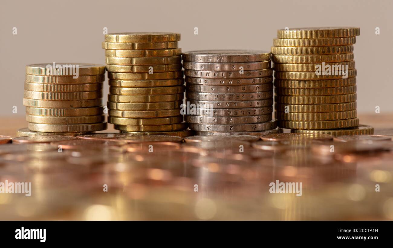 Pile di monete in euro con monete sfocate in primo piano Foto Stock