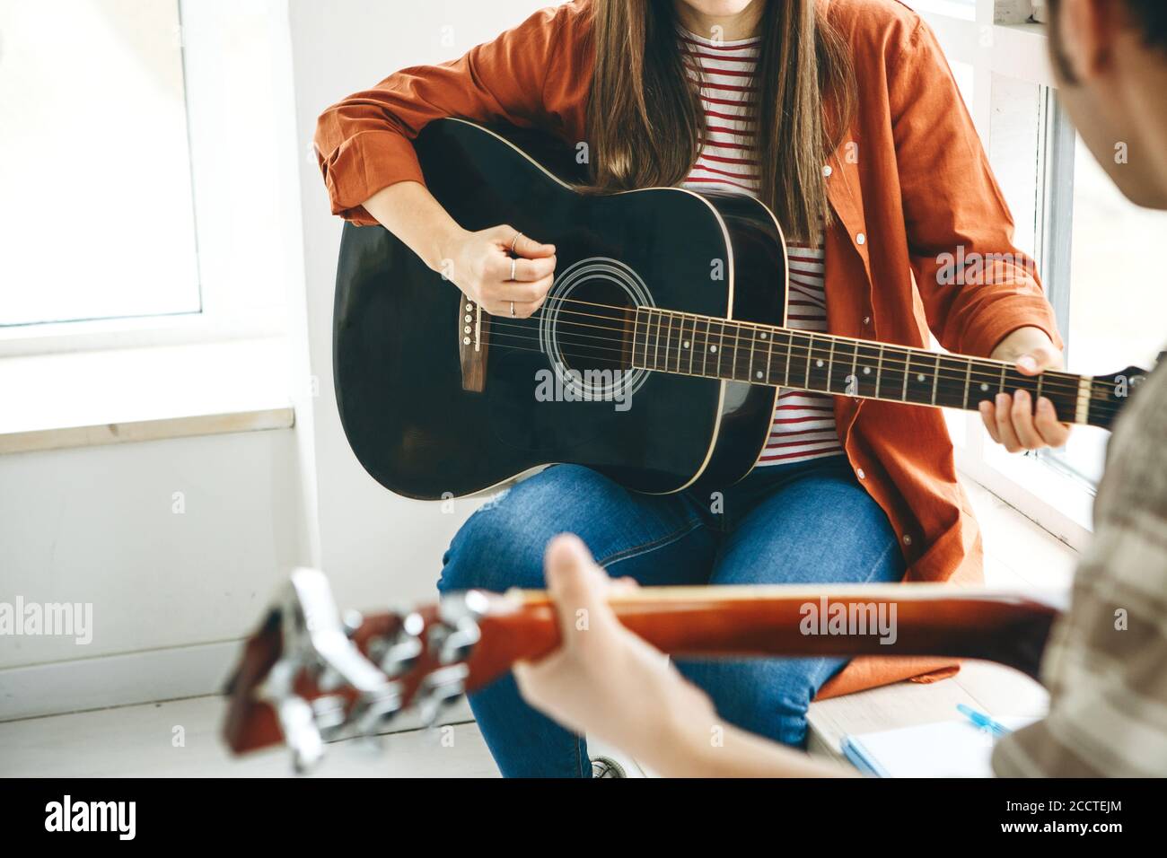 Imparare a suonare la chitarra. L'insegnante spiega allo studente le basi per suonare la chitarra. Lezioni individuali di scuola domestica o extracurricolare. Foto Stock