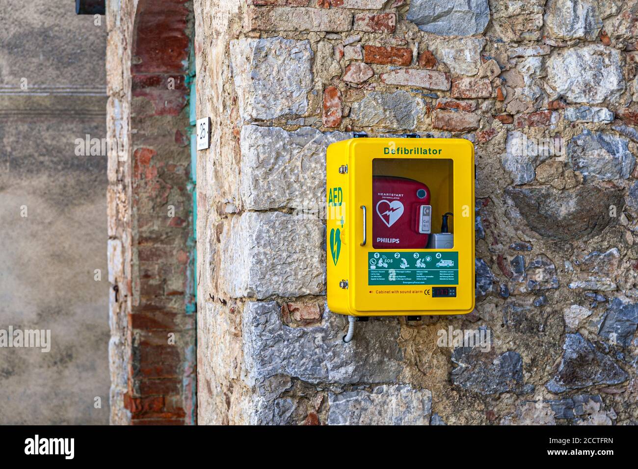 Defibrillatore su un muro di pietra di una casa a Rocca d'Orcia vicino bagno Vignoni, Val d'Orcia, Italia Foto Stock