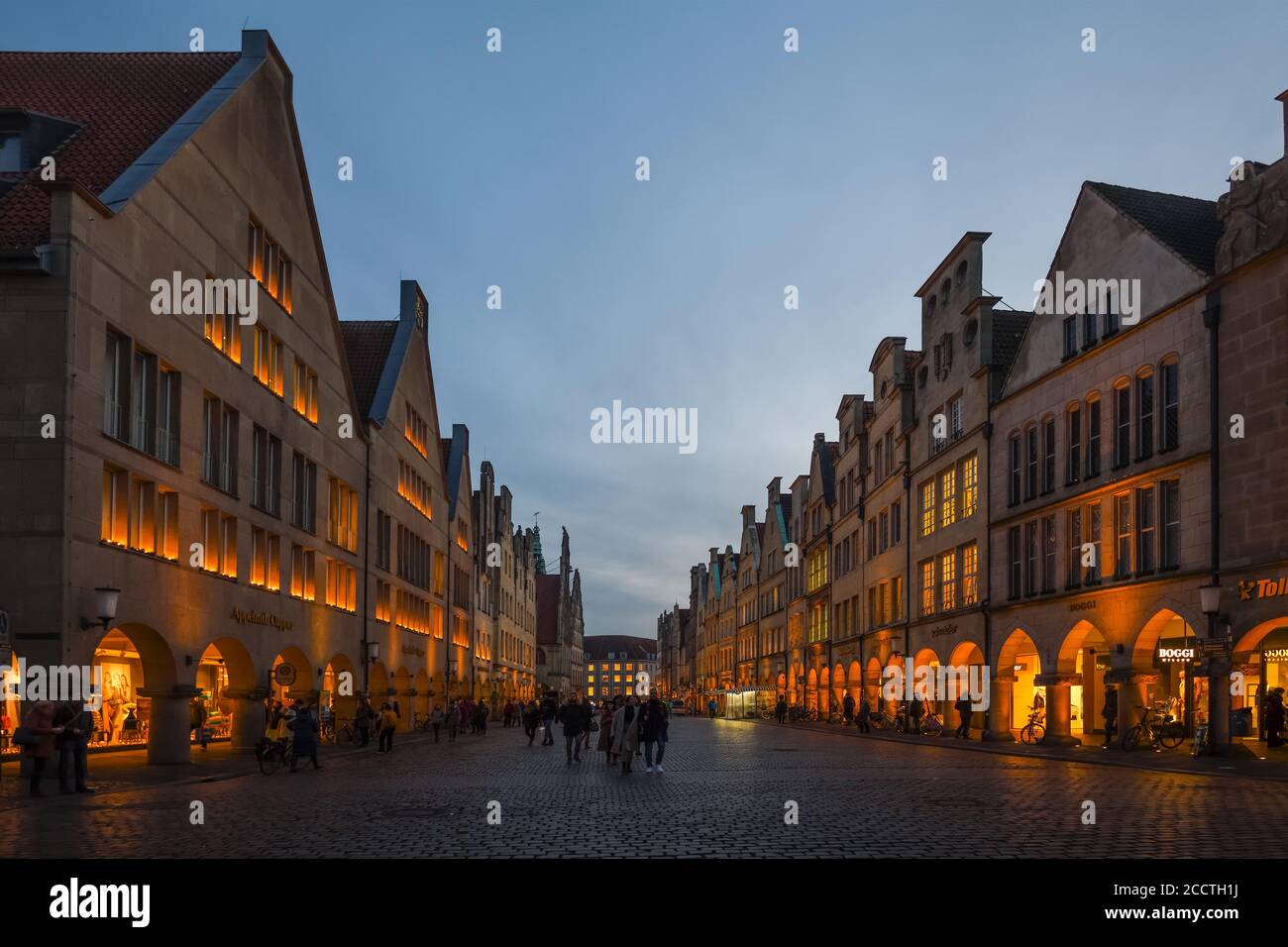 Muenster, Prinzipalmarkt con le sue vecchie case a timpano al tramonto, ora blu, le persone passeggiando per la famosa strada dello shopping, antica strada acciottolata, Foto Stock