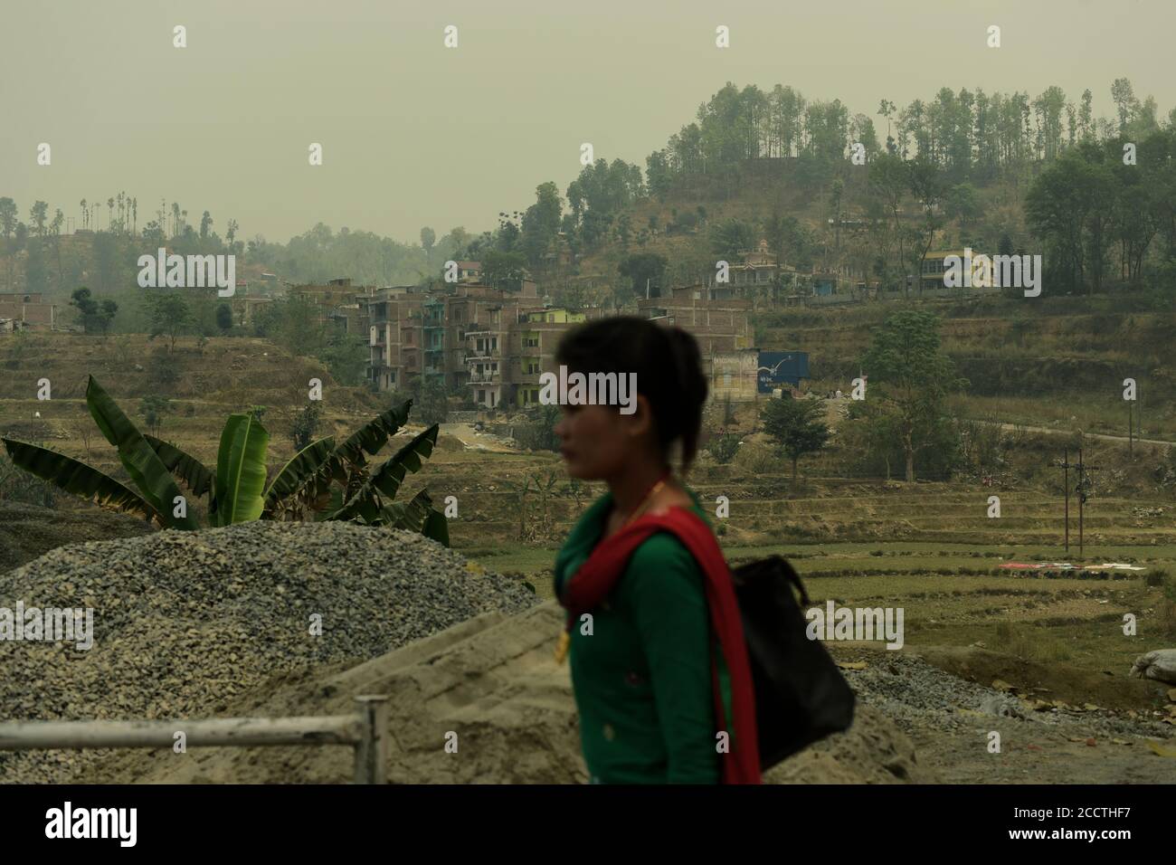 Una donna che cammina nella zona rurale, sul lato di una strada che collega Pokhara e Kathmandu nella provincia di Gandaki Pradesh in Nepal. Foto Stock